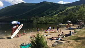 Une plage où des gens se détendent, un poste de surveillance pour les sauveteurs et un lac avec des montagnes en arrière-plan.