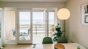 A dining area with a view of the sea, a table with chairs, and a hanging light fixture. - Lovely apartment in Allinge (Allinge)