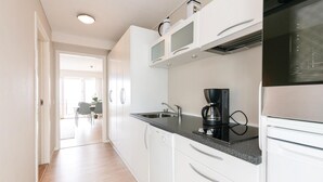 A modern kitchen with white cabinets, a black countertop, and a coffee maker. - Lovely apartment in Allinge (Allinge)