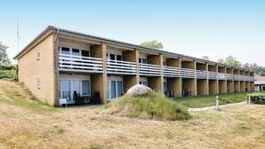 A multi-story building with a brick facade, balconies, and a flat roof. - Lovely apartment in Allinge (Allinge)