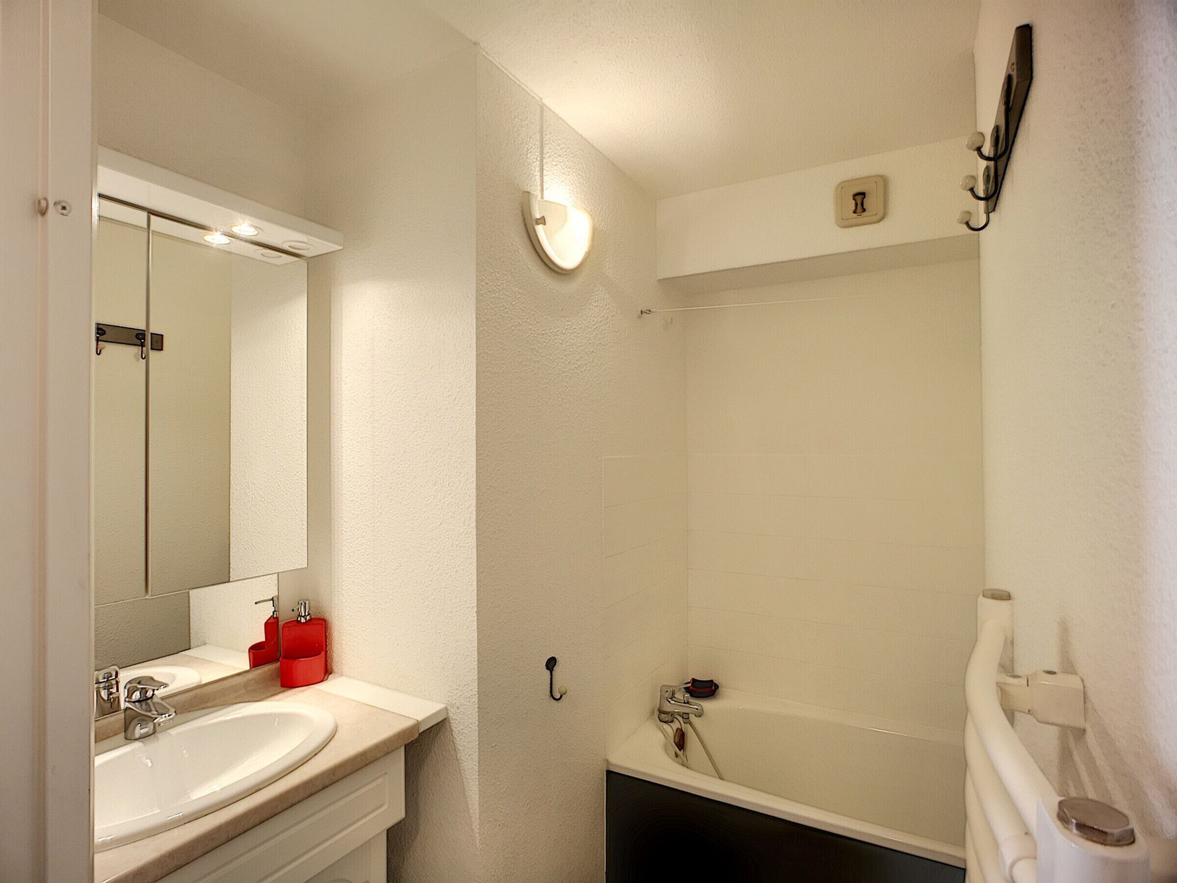 A bathroom with a sink, mirror, and bathtub.