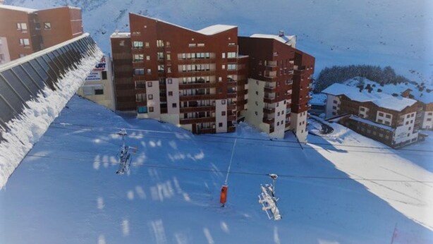 Une station de ski dotée d'un bâtiment moderne, de remontées mécaniques et de pistes enneigées.