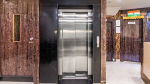 An elevator with a wooden panel design, a sign indicating the office, and a flag decoration. - Treebo Address Inn, Banjara Hills (Hyderabad)