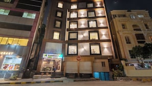 A multi-story building with illuminated windows, a visible restaurant sign, and a storefront with a logo. - Treebo Address Inn, Banjara Hills (Hyderabad)