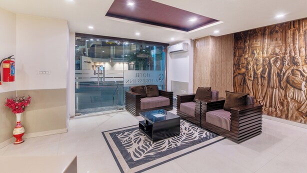 A modern lobby with a glass wall, a fire extinguisher, a decorative vase, and a seating area with a patterned rug. - Treebo Address Inn, Banjara Hills (Hyderabad)