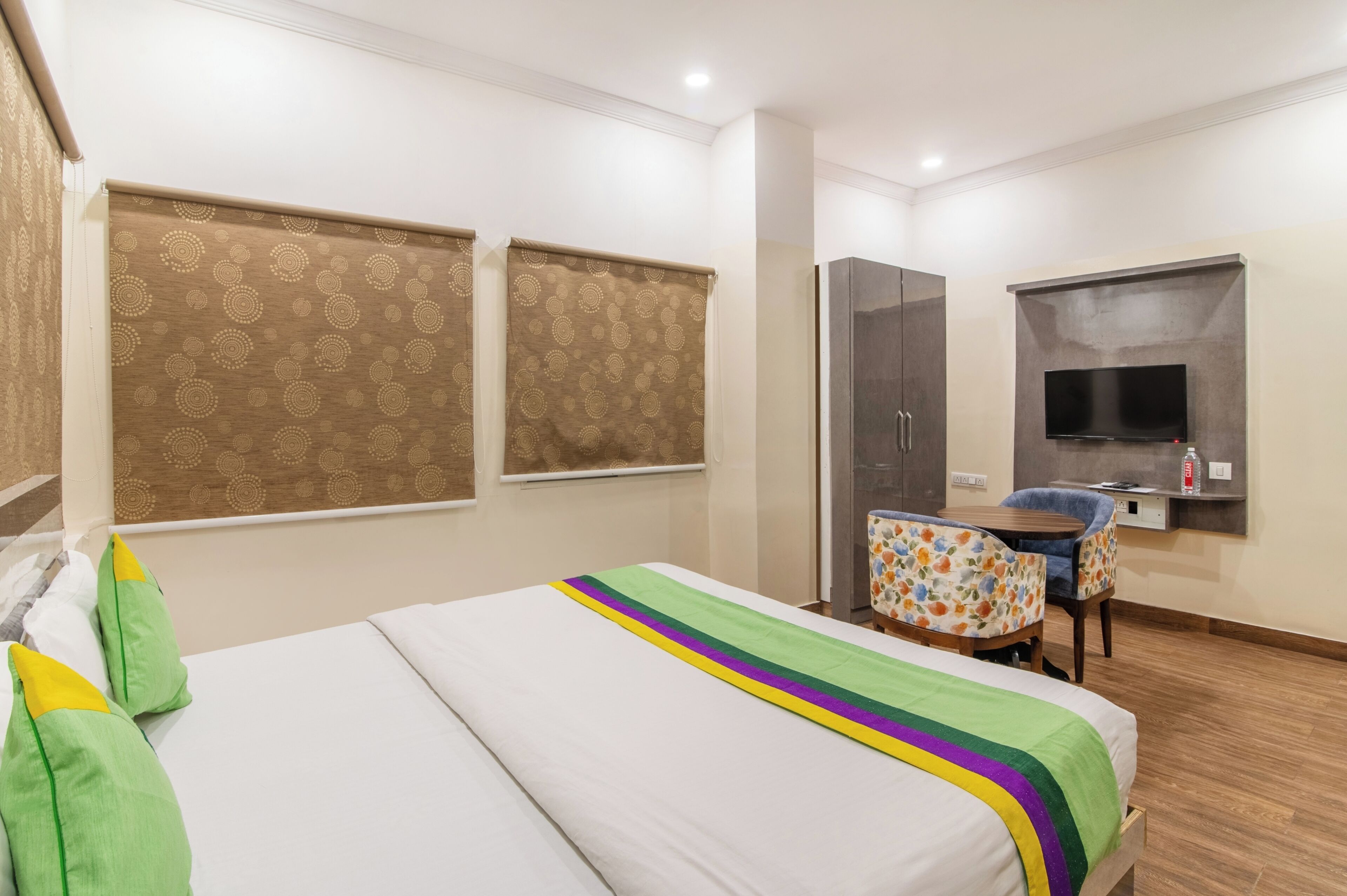 Una habitación de hotel con cama, escritorio con silla, televisor y armario.