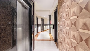 Un pasillo con pared de mármol, pared estampada y piso de baldosas.