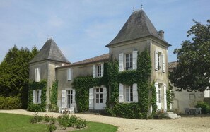 Un grand bâtiment historique, doté de deux tours imposantes et de murs recouverts de lierre.