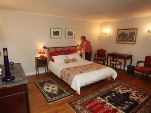 Une chambre à coucher comprenant un lit, des tables de chevet, un bureau et des chaises.