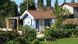 Una pequeña casa de un solo piso con techo de tejas y un jardín delantero.