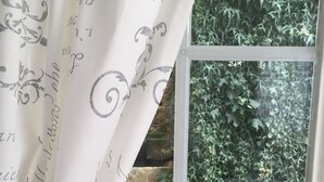 Una ventana con marco blanco y cortina con escritura cursiva.