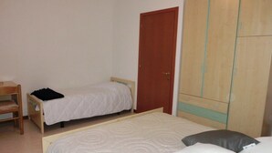 Un dormitorio con dos camas individuales, un armario de madera y un escritorio con una silla.