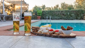 Two glasses of beer and a tray with various snacks by a poolside. - La Casa Medioevale B&B (Lamporecchio)