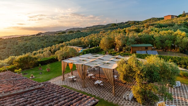 A terrace with a pergola, outdoor seating, and a view of a hilly landscape. - La Casa Medioevale B&B (Lamporecchio)