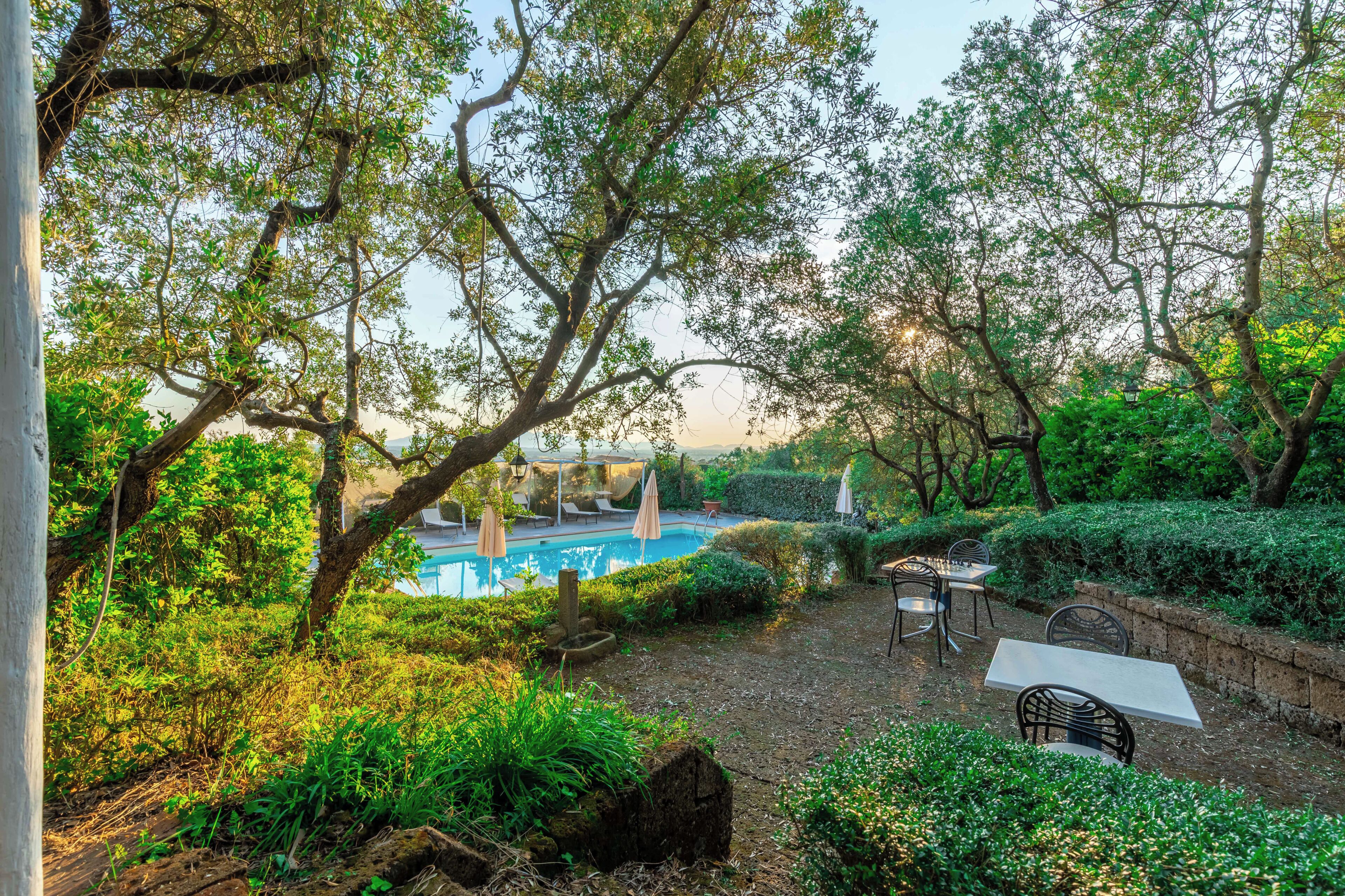 Ein Pool, umgeben von üppiger Vegetation und Sitzgelegenheiten im Freien.