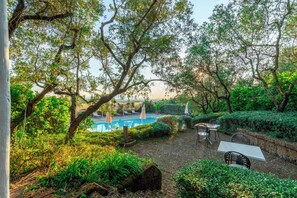 A pool surrounded by lush greenery and outdoor seating. - La Casa Medioevale B&B (Lamporecchio)