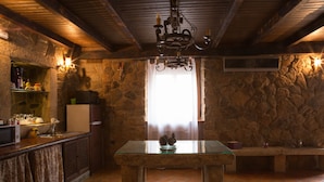 Una cocina rústica con paredes de piedra, techo de madera y una mesa de cristal con un centro de mesa de velas.