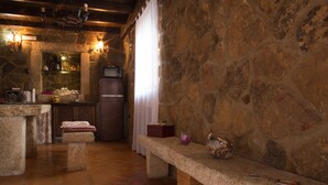 Una cocina rústica con paredes de piedra, un horno microondas empotrado y suelo de ladrillo.