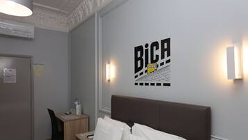Een hotelkamer met een bed, een bureau, een stoel en een wandlamp.