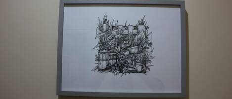 Un dibujo en blanco y negro enmarcado de un castillo rodeado de follaje y una botella.