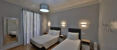 Une chambre d’hôtel avec deux lits, un miroir, un luminaire au plafond et un appliques murale.