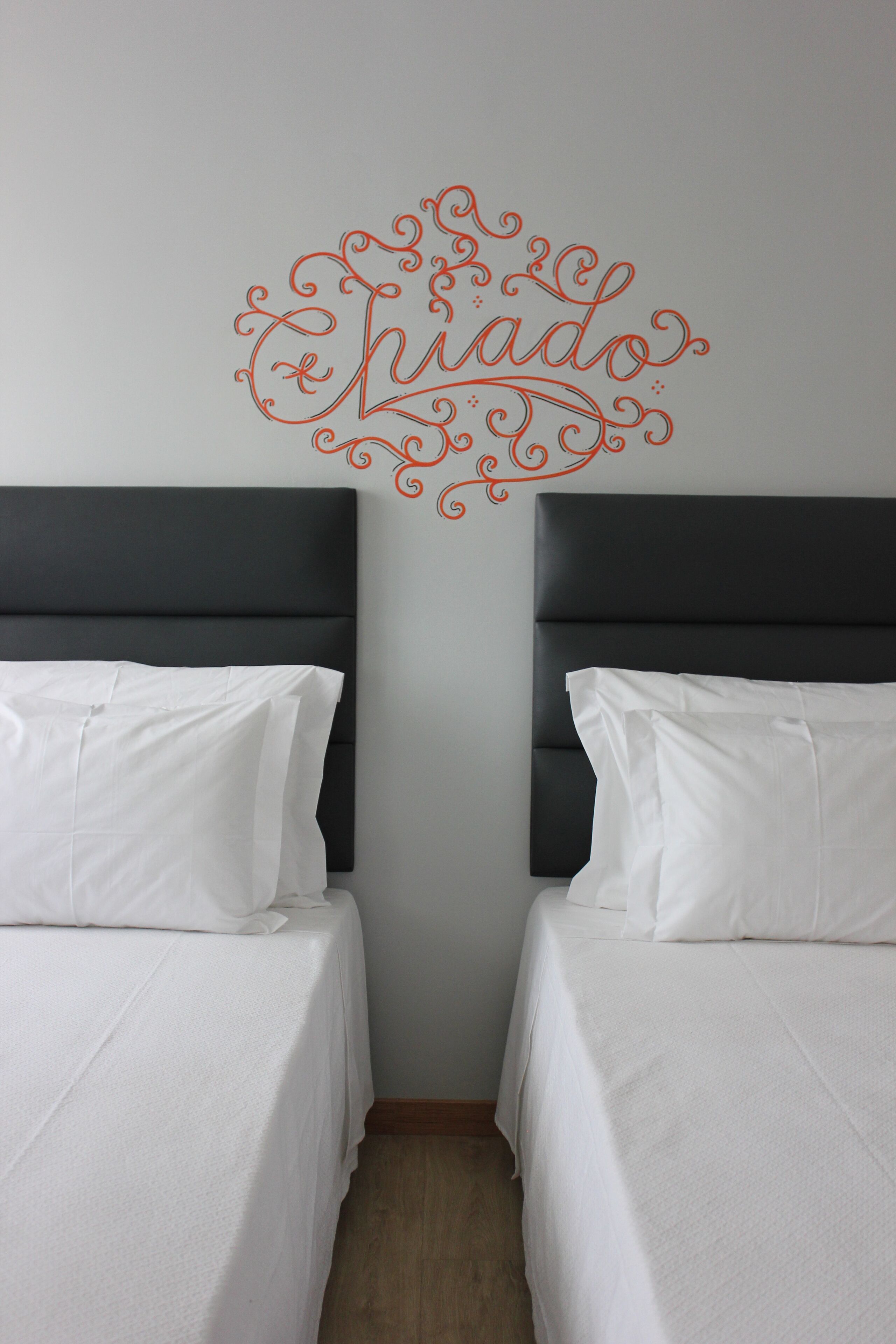 A hotel room with two beds, dark headboards, and a decorative wall sign.