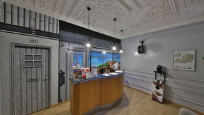 A reception area with a wooden counter, a number 107 door, and a window with a view of greenery. - O Elétrico Guesthouse (Lisbon)