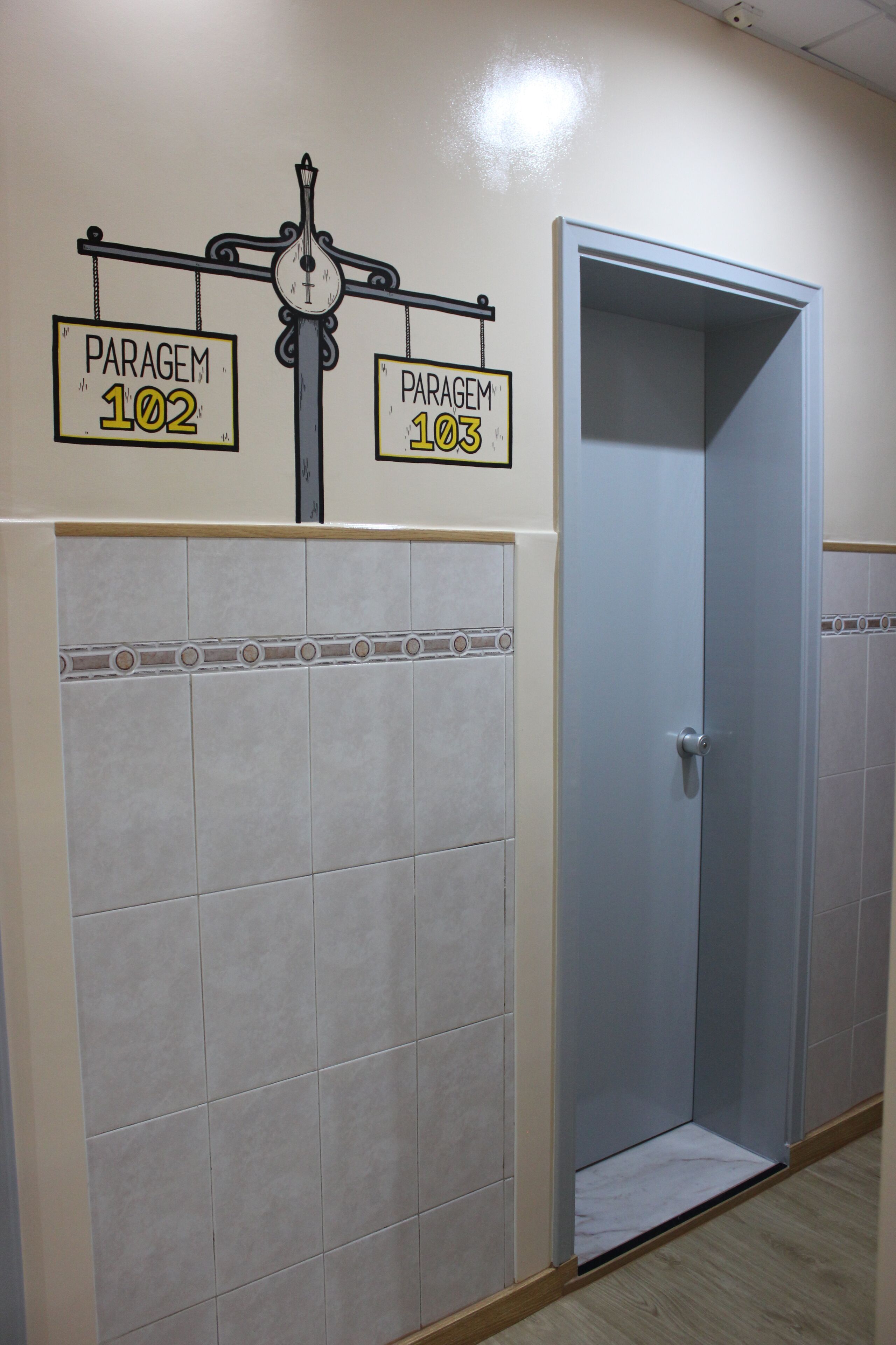 A hallway with two doors labeled "PARAGEM 102" and "PARAGEM 103".