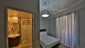 A modern hotel room with a glass shower, a large bed, and a separate bathroom with a vanity. - O Elétrico Guesthouse (Lisbon)