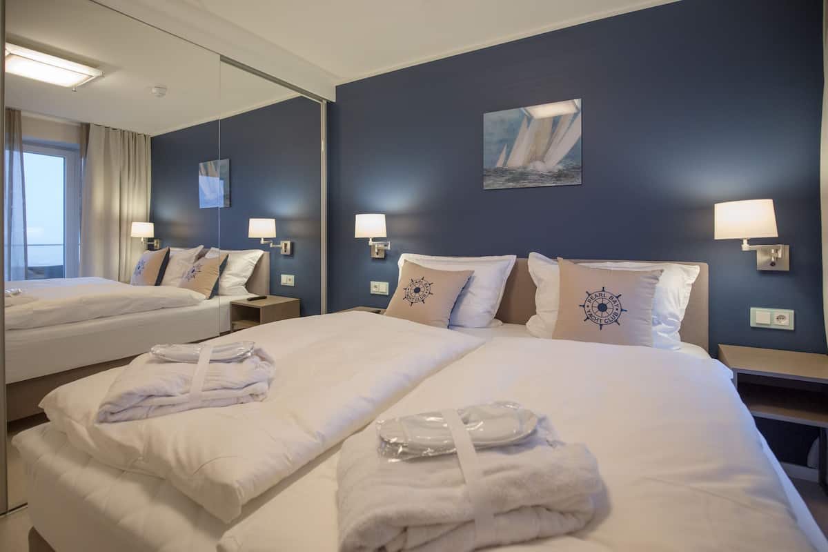 Ett hotellrum med två sängar, en stor spegel och en tavla på väggen.