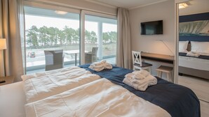 Habitación de hotel con una cama grande, un escritorio, una silla, un televisor y vistas al exterior.