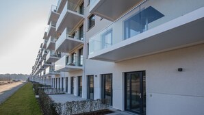 Un edificio residencial moderno de varios pisos, con balcones, ventanas grandes y un diseño minimalista y limpio.