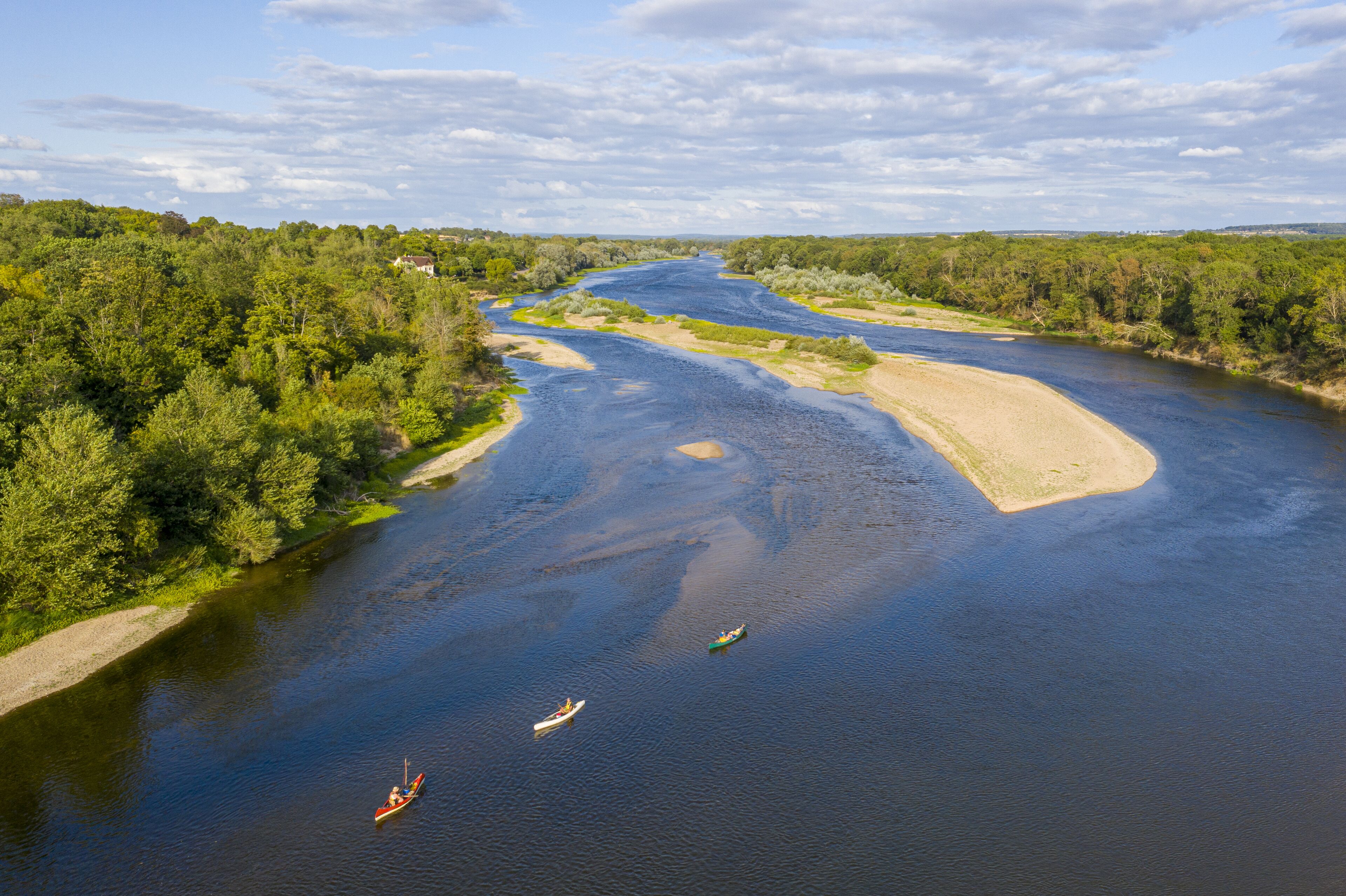 Un río con barcos, rodeado de vegetación exuberante y un cielo despejado.