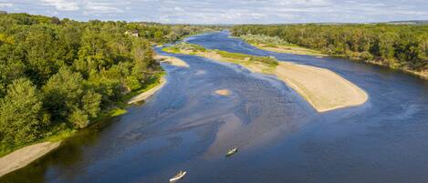 Un río con barcos, rodeado de vegetación exuberante y un cielo despejado.