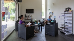A modern indoor space with wicker furniture, a flat-screen TV, and a bookshelf. - Camping de Nevers (Nevers)