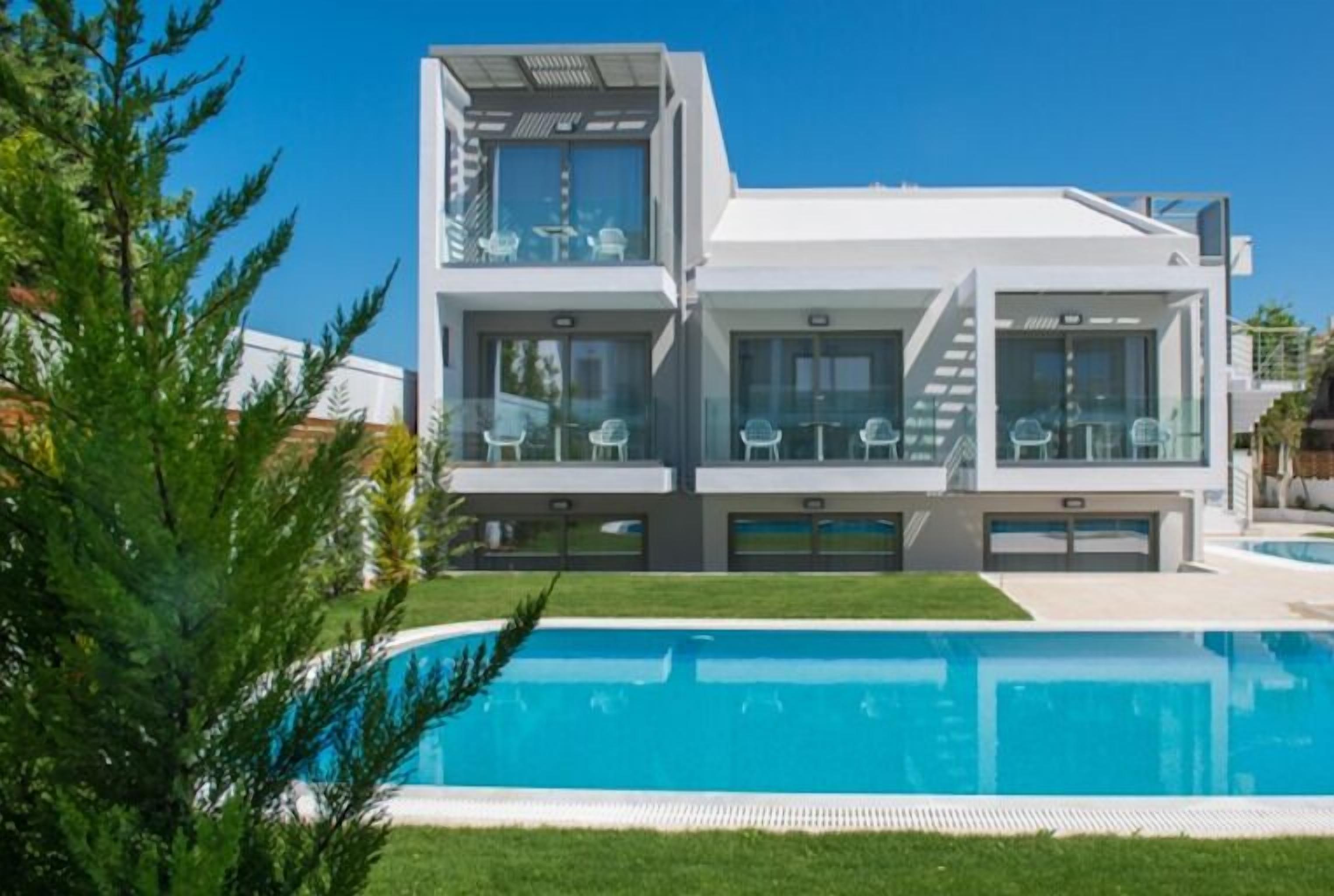 A modern two-story house with a swimming pool in the foreground.