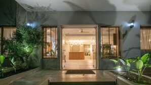 L’entrée d’un hôtel avec un comptoir d’accueil, un ventilateur de plafond et un intérieur bien éclairé.