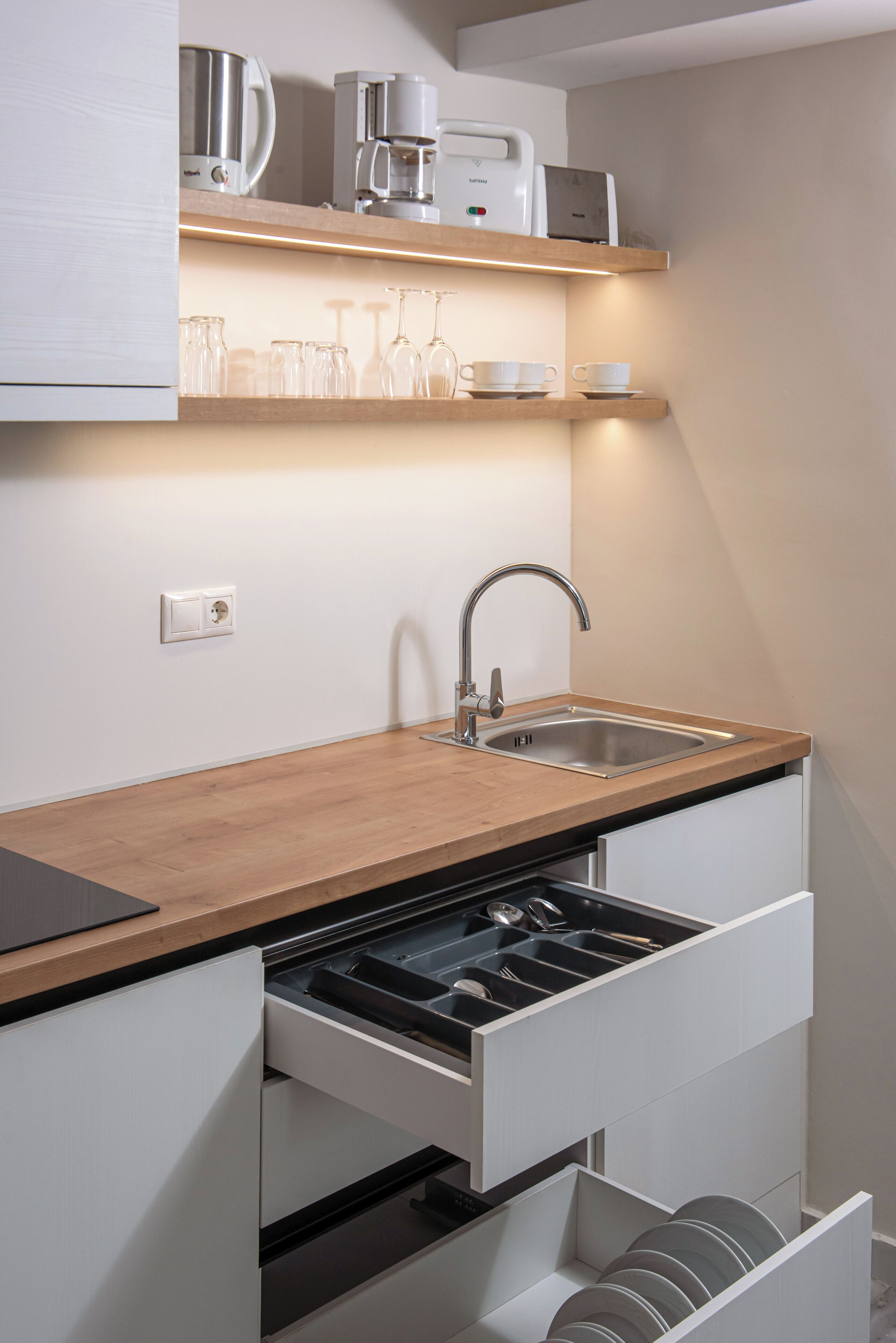Una cocina moderna con encimera de madera, lavavajillas integrado y cafetera.