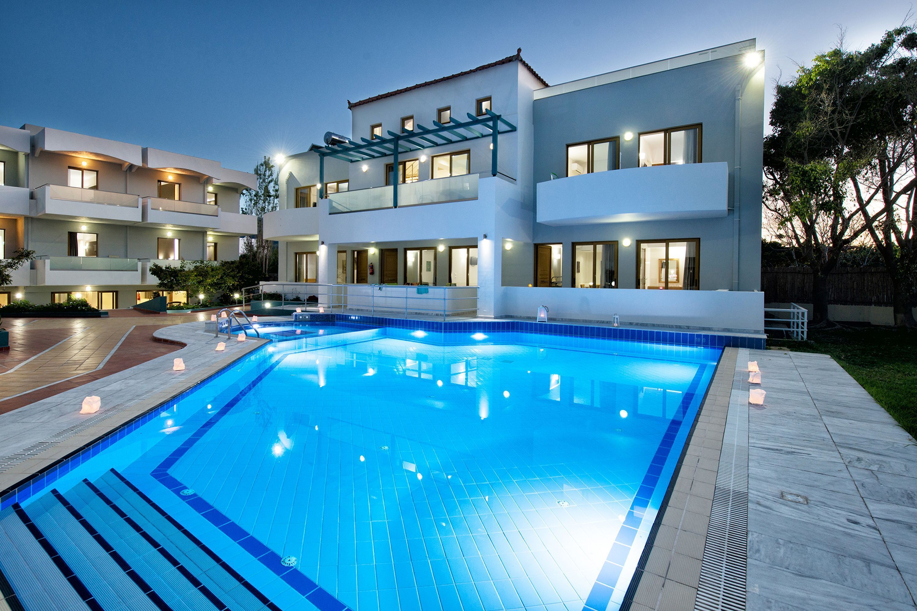 A modern hotel with a swimming pool, multiple balconies, and a well-lit exterior.
