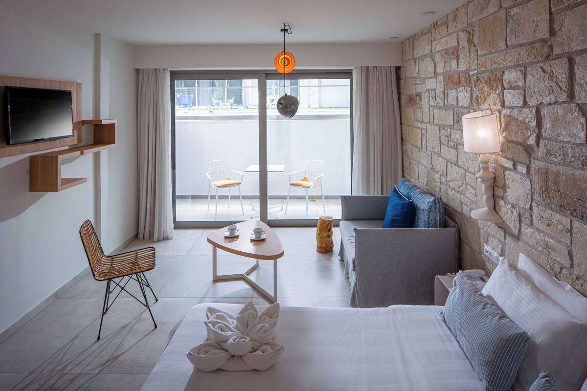 Ett modernt hotellrum med en stor säng, en soffa, ett litet bord och en tv som är monterad på väggen.