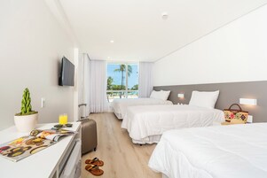 Habitación de hotel con dos camas, un televisor, un escritorio con una revista, una maleta y una planta.