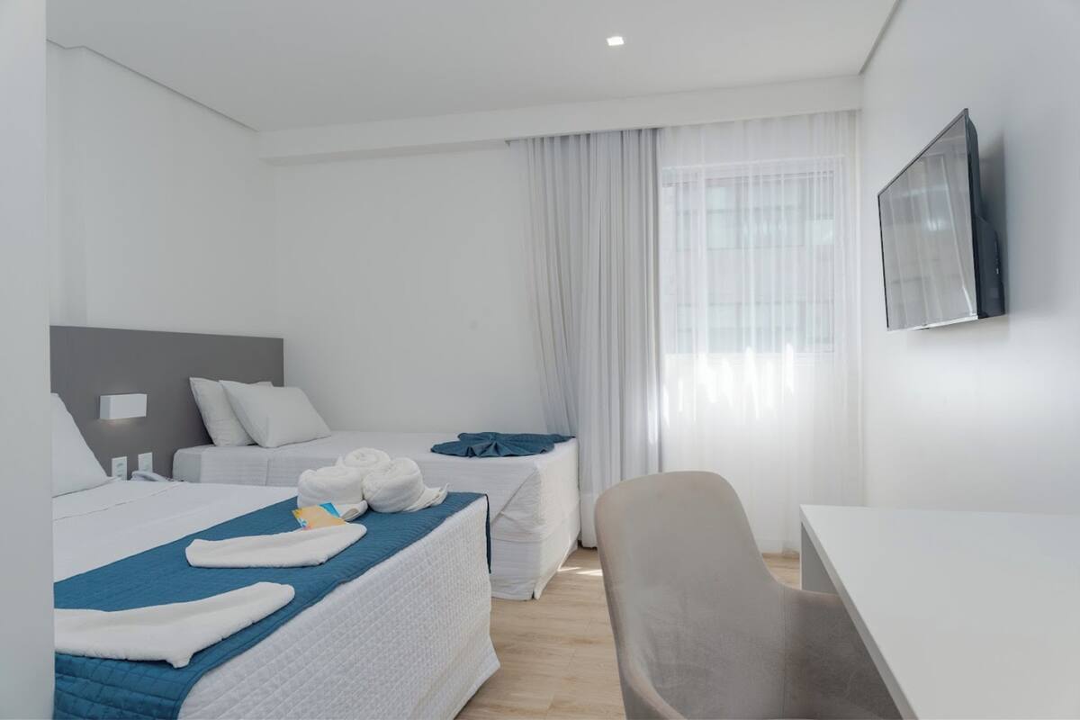 Een hotelkamer met twee bedden, een bureau en een stoel.