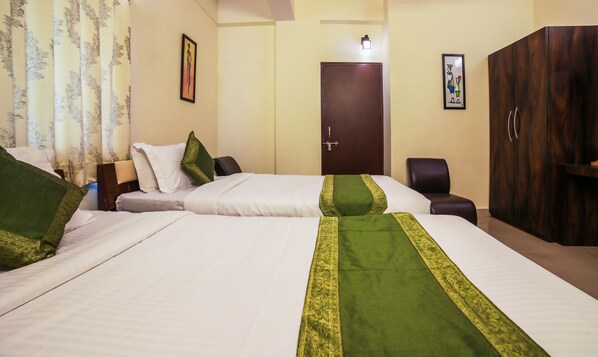 A hotel room with two beds, a wardrobe, a desk, and a door.