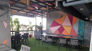 An outdoor seating area with tables and chairs, a colorful geometric wall, and artificial grass. - Treebo Ivory House (Nagpur)