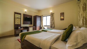 A hotel room with two beds, a desk, a television, and a window with curtains. - Treebo Ivory House (Nagpur)