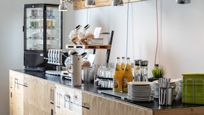 A breakfast bar with a coffee machine, fruit juices, and a variety of breakfast items. - a2 HOTELS Plochingen (Plochingen)