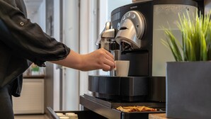 A person using a Nespresso coffee machine to brew coffee. - a2 HOTELS Plochingen (Plochingen)