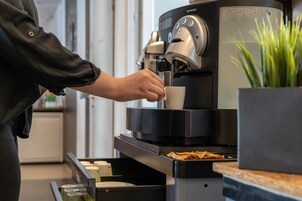 Uma pessoa usando uma máquina de café Nespresso para preparar café.