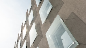 A modern building with multiple rectangular windows and a visible street lamp. - a2 HOTELS DENKENDORF (Denkendorf)
