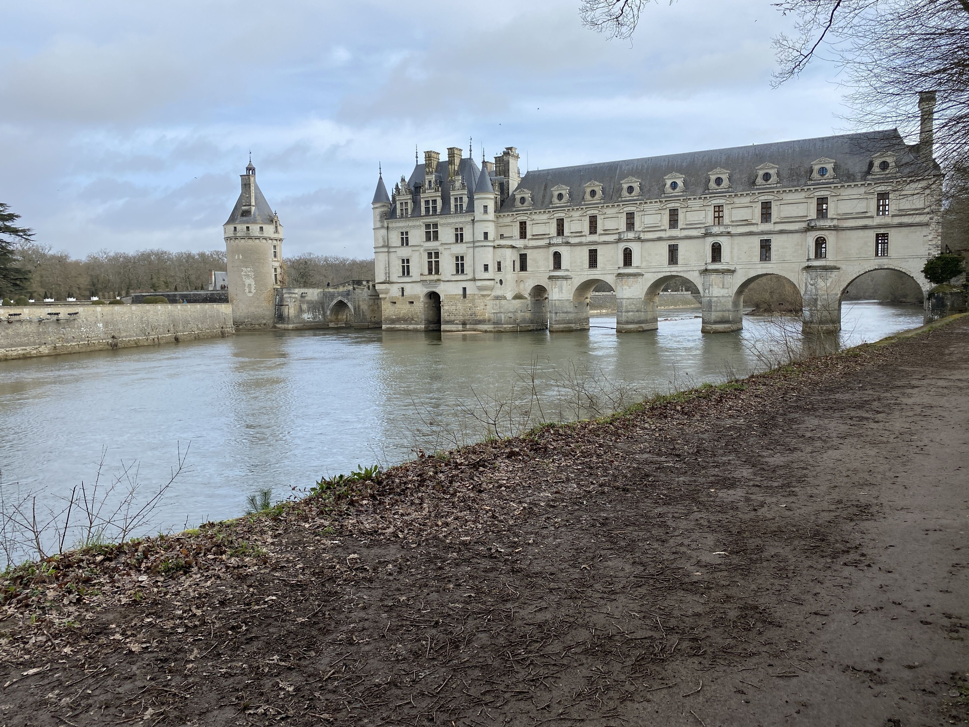 Un bâtiment historique doté de plusieurs arcades enjambant une rivière, ainsi qu’une tour et un pont.
